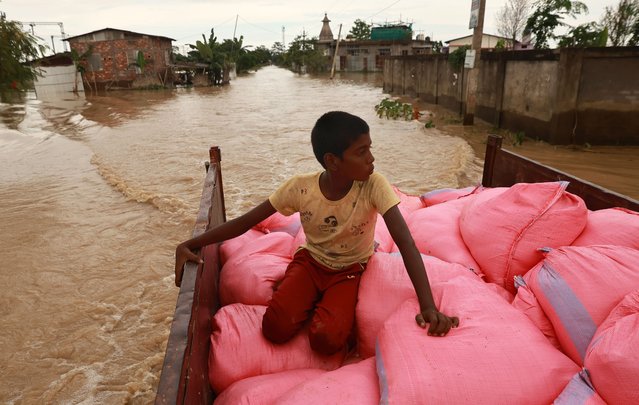 A boy accompanies the transport of relief material on a tractor trolley for flood affected people in the flooded Jamunamukh village, Hojai district of Assam, India, 04 July 2024. According to the daily flood report from the Assam State Disaster Management Authority (ASDMA), two individuals lost their lives in Tezpur, Sonitpur district. Over 1.625 million people have been affected by floods across Barpeta, Biswanath, Cachar, Charaideo, Chirang, Darrang, and Dhemaji districts. Currently, the state administration is running 515 relief camps and distribution centers across 24 districts, providing shelter to 386,950 people. (Photo by Rajat Gupta/EPA)