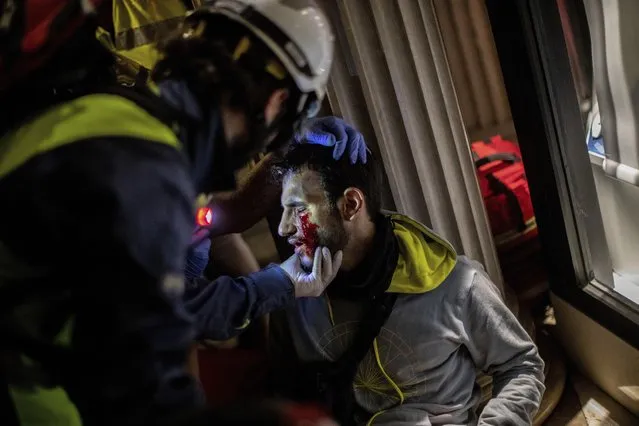 Paramedics attend a protestor during clashes with police in Barcelona, Spain, early Friday, October 18, 2019. Catalonia's separatist leader vowed Thursday to hold a new vote to secede from Spain in less than two years as the embattled northeastern region grapples with a wave of violence that has tarnished a movement proud of its peaceful activism. (Photo by Bernat Armangue/AP Photo)