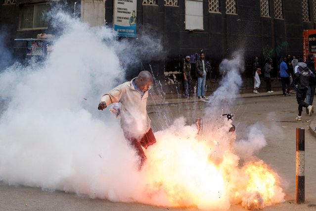 A teargas canister detonates as a protestor attempts to kick it back in the direction of the police during anti-government protests in Nairobi on July 16, 2024. Police were out in force in the centre of Kenya's capital on Tuesday after calls for more demonstrations against the embattled government of President William Ruto. Activists led by young Gen-Z Kenyans launched peaceful rallies a month ago against deeply unpopular tax hikes but they descended into deadly violence last month, prompting Ruto to drop the planned increases. (Photo by Tony Karumba/AFP Photo)