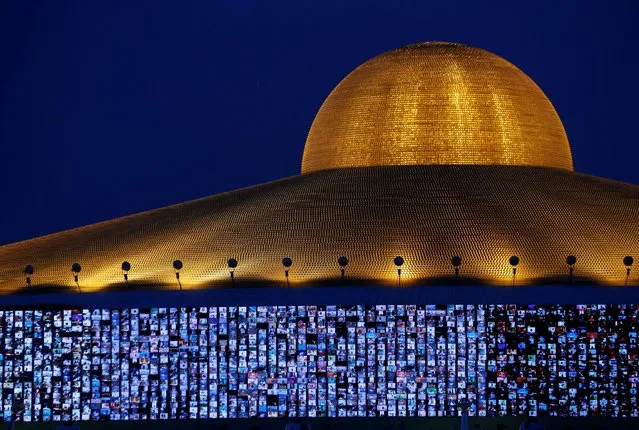 Screens show devotees gathering via Zoom application during a ceremony to commemorate Makha Bucha Day at the Wat Phra Dhammakaya temple, following the spread of the coronavirus disease (COVID-19), in Pathum Thani province, Thailand, February 16, 2022. (Photo by Soe Zeya Tun/Reuters)\
