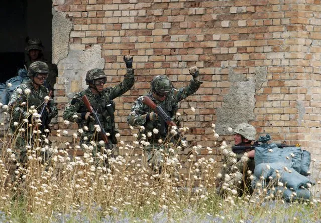 Bulgarian soldiers gesture as they approach Georgian soldier (R) during a joint military exercise with NATO members, called “Agile Spirit 2015” at the Vaziani military base outside Tbilisi, Georgia, July 21, 2015. (Photo by David Mdzinarishvili/Reuters)
