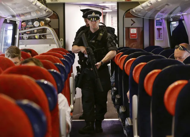 Armed British Transport Police Specialist Operations officers on board a  train to Birmingham New Street at Euston station in London as armed police officers are patrolling on board trains nationwide for the first time Thursday May 25, 2017. British Transport Police announced the measure in a bid to “disrupt and deter criminal activity” on the rail network after the UK terror threat level rose to critical in the wake of the Manchester attack. (Photo by Yui Mok/PA Wire via AP Photo)