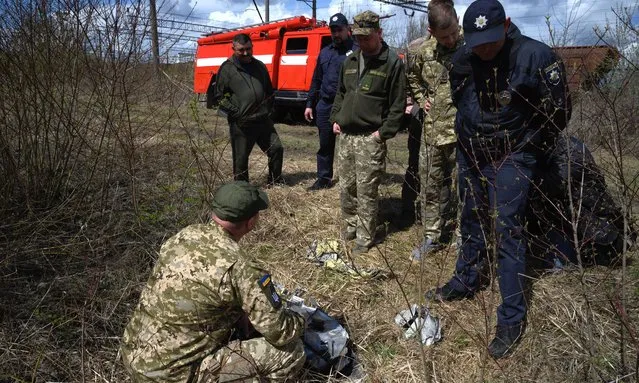 Officials look at shards of twisted metal from a Russian rocket in undergrowth near a train line on April 25, 2022 near Lviv, Ukraine. The head of Ukrainian Railways said in a social media post today that five rail facilities had been attacked by Russia this morning, including a “traction substation”, a facility supplying power to overhead lines, in Krasne, near Lviv. (Photo by Leon Neal/Getty Images)