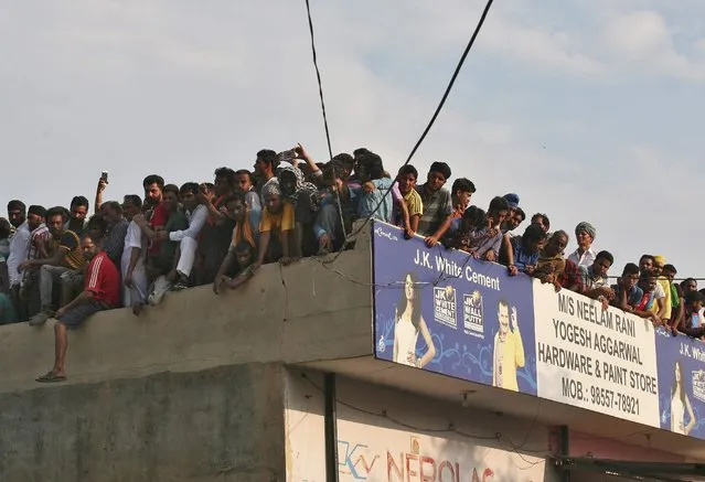 Onlookers stand atop an adjoining building to look at the site of a gunfight in Dinanagar town in Gurdaspur district of Punjab, India, July 27, 2015. (Photo by Mukesh Gupta/Reuters)