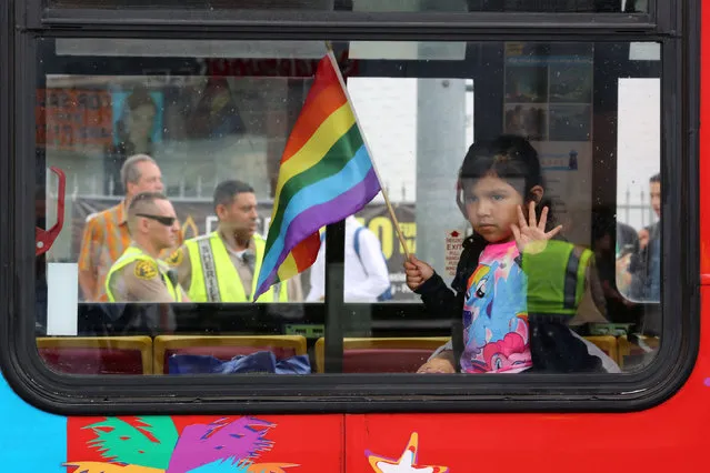 Los Angeles County Sheriff's deputies are seen behind a girl riding in a bus at the 46th annual Los Angeles Gay Pride Parade in West Hollywood, California, after a gunman opened fire at a gay nightclub in Orlando, Florida U.S. June 12, 2016. (Photo by David McNew/Reuters)