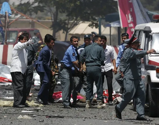 Men carry a casualty to an ambulance at the site of a car bomb blast at the entrance gate to the Kabul airport in Afghanistan August 10, 2015. (Photo by Ahmad Masood/Reuters)