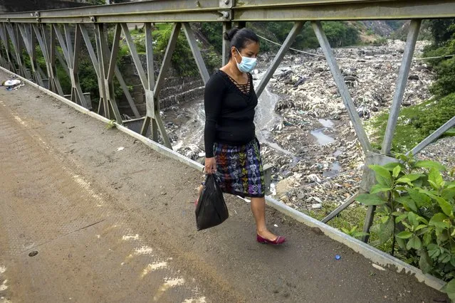 A woman walks over Las Vacas river bridge in Chinautla, on the outskirts of Guatemala City, Wednesday, June 8, 2022. The Ocean Cleanup NGO is currently piloting a trash collection device in one of the world's most polluted rivers, the Las Vacas river, where unique seasonal challenges include huge quantities of waste and massive water pressure during the rainy season. (Photo by Moises Castillo/AP Photo)