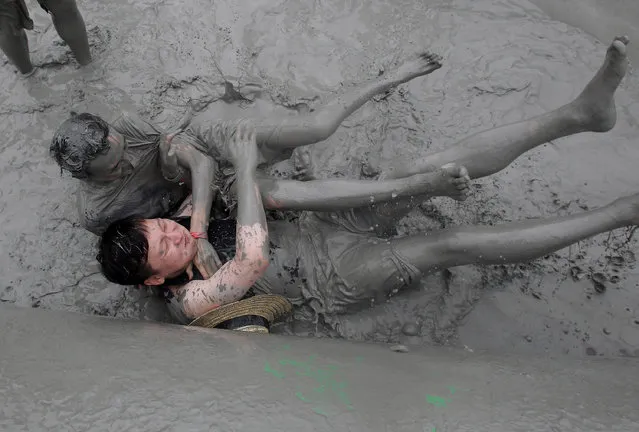 Festival goers wrestle in the mud during the annual Boryeong Mud Festival at Daecheon Beach on July 18, 2014 in Boryeong, South Korea. The mud, which is believed to have beneficial effects on the skin due to its mineral content, is sourced from mud flats near Boryeong and transported to the beach by truck. (Photo by Chung Sung-Jun/Getty Images)