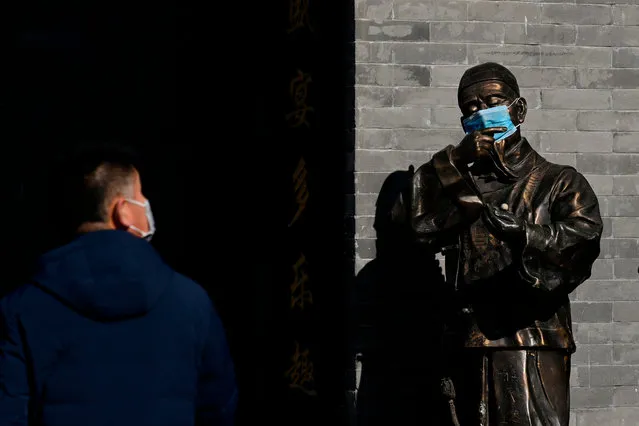 A bronze statue wearing a mask is seen at the entrance of a shop along a business street in Beijing on February 4, 2020. The number of total infections in China's coronavirus outbreak has passed 20,400 nationwide with 3,235 new cases confirmed, the National Health Commission said on February 4. (Photo by Wang Zhao/AFP Photo)