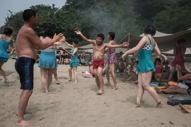 A photo taken on July 22, 2017 shows beach- goers dancing at the West Sea Barrage beach outside the coastal city of Nampo, southwest of Pyongyang. (Photo by Ed Jones/AFP Photo)