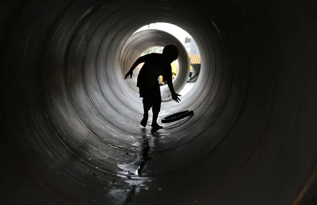 A Filipino boy plays inside a large metal tube that will be used to repair an old bridge in suburban Malabon, north of Manila, Philippines, Tuesday, July 22, 2014. (Photo by Aaron Favila/AP Photo)