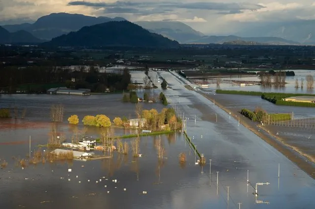 Rising flood water surround a home and cover Highway 1 in Abbotsford, British Columbia, Tuesday, November 16, 2021. Abbotsford Mayor Henry Braun said impassable highways were creating havoc in his city as police and firefighters tried to get people to evacuation centers. Sunny skies followed two days of torrential storms that dumped the typical amount of rain that the city gets in all of November, but the mayor said the water was still rising and Highway 1 would be cut shut down for some time. (Photo by Jonathan Hayward/The Canadian Press via AP Photo)