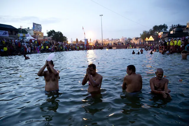 Indian devotees perform rituals as they take holy dips in the Godavari River during Kumbh Mela, or Pitcher Festival, in Nasik, India, Wednesday, August 26, 2015. Hindus believe taking a dip in the waters of a holy river during the festival will cleanse them of their sins. Wednesday marked the first day of bathing for those attending this year's festival on the banks of the Godavari River in Maharashtra state. (Photo by Tsering Topgyal/AP Photo)