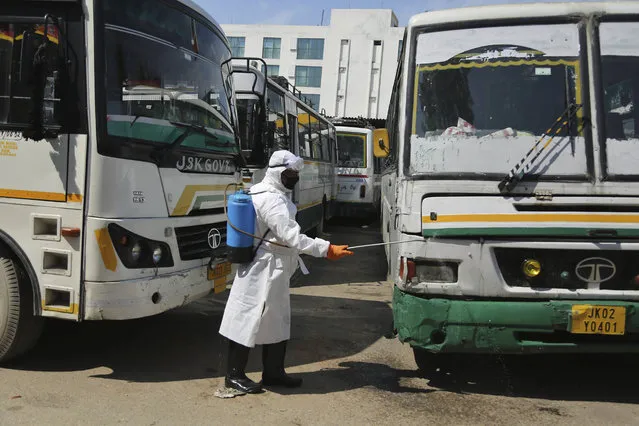 An Indian health worker sprays disinfects on a state passenger bus as a precaution against COVID-19 in Jammu, India, Monday, March 16, 2020. For most people, the new coronavirus causes only mild or moderate symptoms. For some, it can cause more severe illness, especially in older adults and people with existing health problems. (Photo by Channi Anand/AP Photo)