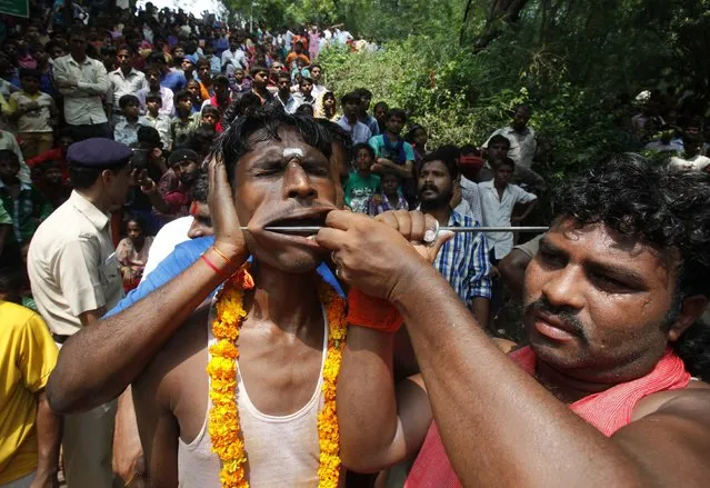 A Hindu devotee gets his cheeks pierced as he takes part in an annual religious procession called “Shitla Mata” in the northern Indian city of Chandigarh August 10, 2014. Hindu devotees subject themselves to painful rituals during the religious procession to demonstrate their faith and as a penance to the deity at a temple dedicated to the goddess Shitla. (Photo by Ajay Verma/Reuters)