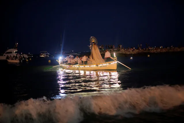 Men in traditional costumes sail in a float carrying a statue of the El Carmen Virgin during a procession in Malaga, southern Spain, July 16, 2016. Many seaside towns celebrate the annual feast of the El Carmen Virgin, who is worshipped as the patron saint of sailors. (Photo by Jon Nazca/Reuters)