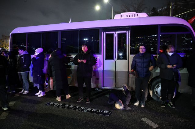 A woman lies on a road to block a vehicle transporting an army unit, after South Korean President Yoon Suk Yeol declared martial law, in Seoul, South Korea, on December 4, 2024. (Photo by Kim Hong-Ji/Reuters)