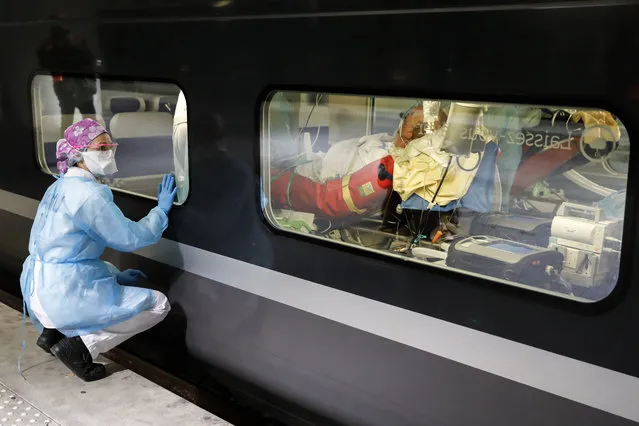 A medical staff watches from a platform of the Gare d'Austerlitz train station on April 1, 2020 in Paris through the window of a medicalised TGV high speed trains before its departure to evacuate patients infected with the COVID-19 from Paris' region hospitals to other hospitals in the western France Brittany region where the outbreak has been limited so far. France has been on lockdown since March 17 in a bid to limit the contagion caused by the novel coronavirus, a situation it has extended until at least April 15. (Photo by Thomas Samson/AFP Photo)