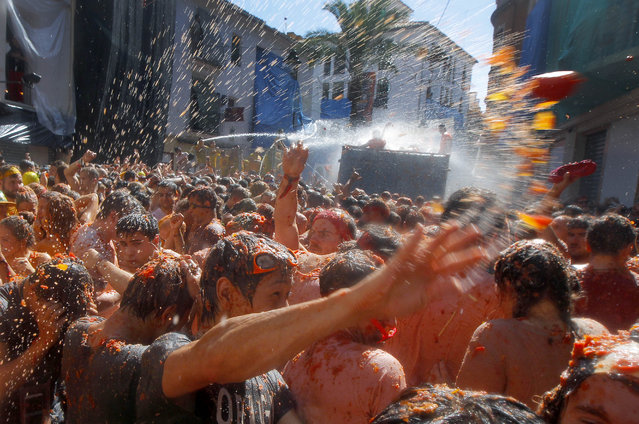 Crowds of people throw tomatoes at each other during the annual “Tomatina” tomato fight fiesta in the village of Bunol, 50 kilometers outside Valencia, Spain, Wednesday, August 27, 2014. (Photo by Alberto Saiz/AP Photo)