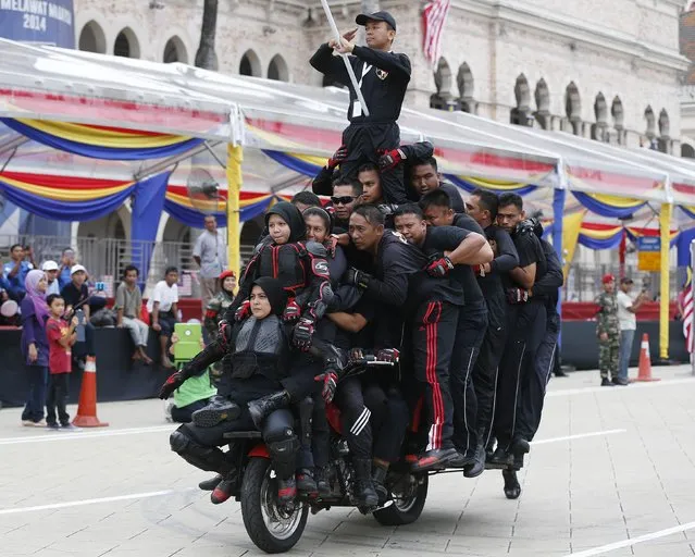 Thirty-one stunt riders balance on a motorcycle during dress rehearsals for the upcoming Independence Day celebrations in Kuala Lumpur August 28, 2014. (Photo by Olivia Harris/Reuters)