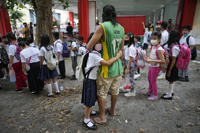 A girl holds on to his father during the opening of classes at the San Juan Elementary School in Pasig, Philippines on Monday, August 22, 2022. Millions of students wearing face masks streamed back to grade and high schools across the Philippines Monday in their first in-person classes after two years of coronavirus lockdowns that are feared to have worsened one of the world's most alarming illiteracy rates among children. (Photo by Aaron Favila/AP Photo)