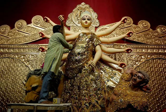 An artisan adorns a gold saree, a traditional Indian women cloth, on an idol of Hindu goddess Durga, at a temporary platform called pandal, ahead of the Durga Puja festival in Kolkata, India September 23, 2017. (Photo by Rupak De Chowdhuri/Reuters)