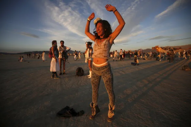 Tracy Sarita celebrates the sunrise during the Burning Man 2015 “Carnival of Mirrors” arts and music festival in the Black Rock Desert of Nevada, September 3, 2015. (Photo by Jim Urquhart/Reuters)