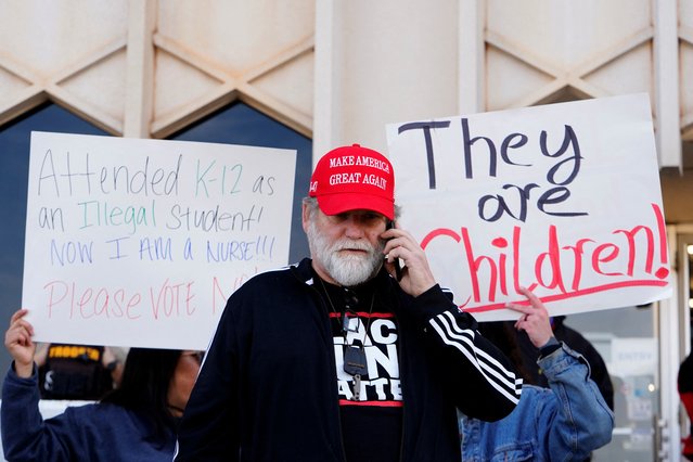 A supporter of U.S. President Donald Trump talks on his phone in front of protesters opposing possible Immigration and Customs Enforcement (ICE) raids in public schools outside the State Department of Education during their monthly board meeting in Oklahoma City, Oklahoma, U.S. January 28, 2025. (Photo by Nick Oxford/Reuters)