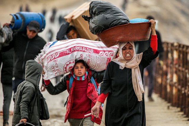 People walk with belongings along al-Rashid street between Gaza City and Nuseirat in the central Gaza Strip on February 10, 2025 as displaced people return home amid the current ceasefire deal in the war between Israel and Hamas. (Photo by Eyad Baba/AFP Photo)