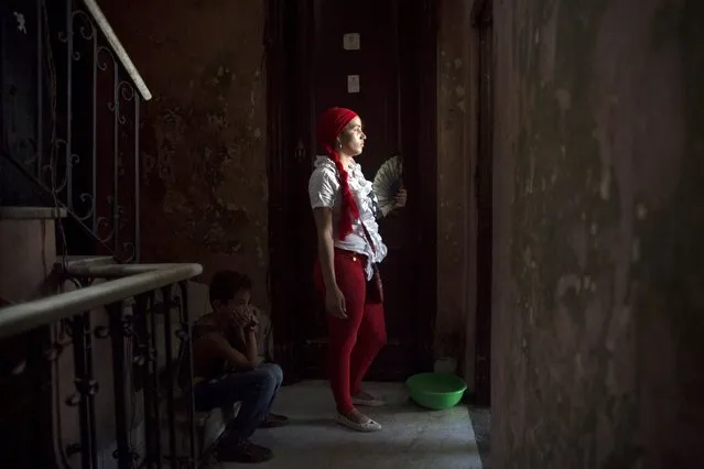 Santeria practitioner Adriana Millarez, 26, gets some fresh air during a ceremony to attract spirits of dead ancestors to ask for guidance in downtown Havana, August 18, 2015. (Photo by Alexandre Meneghini/Reuters)