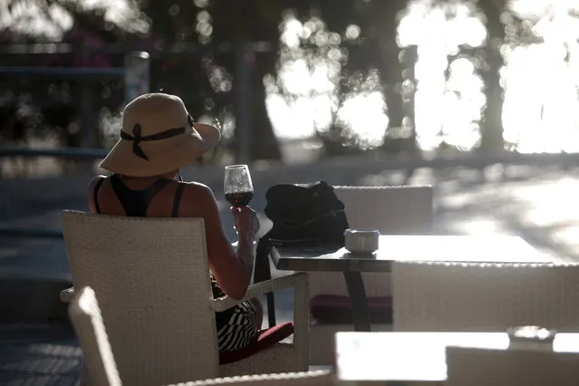 A woman sits in a terrace bar near the beach of Palma de Mallorca, Spain, Monday, June 15, 2020. Borders opened up across Europe on Monday after three months of coronavirus closures that began chaotically in March. (Photo by Joan Mateu/AP Photo)