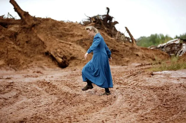 A woman walks across mud and debris in a road following a flash flood, Tuesday, September 15, 2015, in Colorado City, Ariz. Officials say the bodies of two people killed in flash flooding in southern Utah were recovered in Arizona a few miles downstream, while the bodies of six others were recovered in Utah. (Photo by Rick Bowmer/AP Photo)