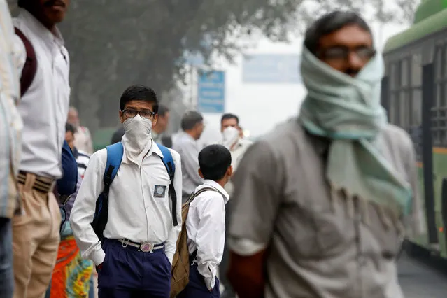 A schoolboy covers his face with a handkerchief as he waits for a passenger bus on a smoggy morning in New Delhi, India, November 8, 2017. (Photo by Saumya Khandelwal/Reuters)