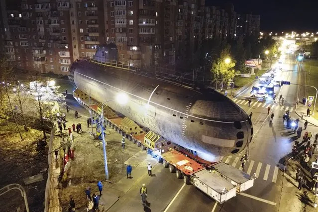 The bow of the Soviet submarine K-3 ”Leninsky Komsomol” is transported by a platform along the street from the pier to the museum where it will be assembled with the stern and installed as a museum, in the city of Kronstadt, outside St. Petersburg, Russia, Wednesday, October 12, 2022. (Photo by Dmitri Lovetsky/AP Photo)