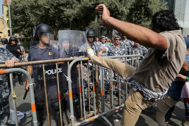 A protester kicks a barrier near riot police that are blocking a street leading to the parliament building where a session of “national dialogue” is taking place between politicians aimed at discussing ways out of a political crisis, in downtown Beirut, Lebanon September 16, 2015. (Photo by Aziz Taher/Reuters)