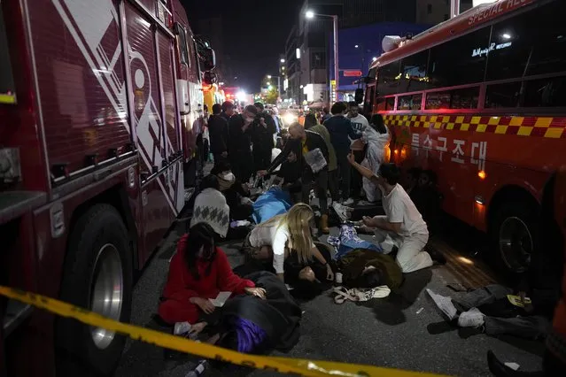 Injuried people are helped at the street near the scene in Seoul, South Korea, early Sunday, October 30, 2022. South Korean officials said around 50 people were in cardiac arrest and a number feared dead after being crushed by a large crowd pushing forward on a narrow street during Halloween festivities in the capital Seoul. (Photo by Lee Jin-man/AP Photo)