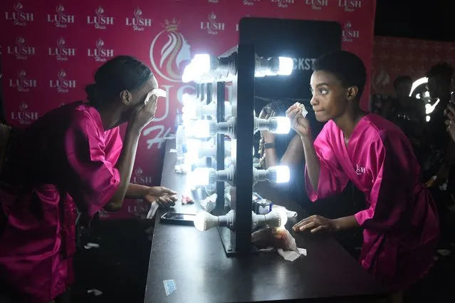 Models apply makeup backstage before walking the runway during the Lagos Fashion Week in Lagos on October 28, 2022. Lagos Fashion Week is held yearly and provides a platform for African designers to present their collections to buyers, media and fashion enthusiasts in Nigeria's commercial capital. (Photo by Pius Utomi Ekpei/AFP Photo)