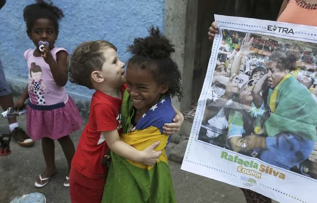 Cousins of Brazilian judoka Rafaela Silva who won the gold medal in the 57 kg judo final, joke beside a newspaper with the picture of her next to the house where she was born at the Cidade de Deus (City of God) slum in Rio De Janeiro, Brazil on August 9, 2016. (Photo by Nacho Doce/Reuters)