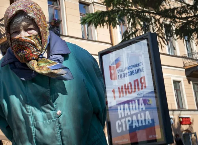 In this photo taken on Tuesday, June 23, 2020, an elderly woman stands near a billboard reading “All-Russian voting, July 1, our country” in St.Petersburg, Russia. Russian authorities seem to be pulling out all the stops to get people to vote on constitutional amendments that would enable President Vladimir Putin to stay in office until 2036. The nationwide vote begins Thursday and lasts for a week. (Photo by Dmitri Lovetsky/AP Photo)