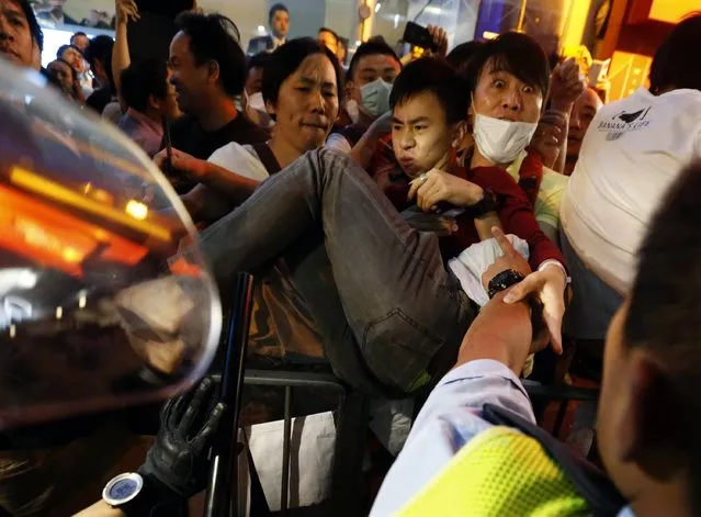 A protester is carried away by other protesters over a fence as he is charged by riot police during a confrontation at Mongkok shopping district in Hong Kong October 17, 2014. Hong Kong riot police used pepper spray and baton charged crowds of pro-democracy protesters on Friday evening as tension escalated after a pre-dawn clearance of a major protest zone in the Chinese-controlled financial hub. (Photo by Bobby Yip/Reuters)