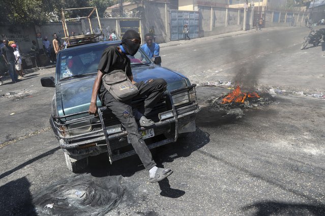 A protester sits on the hood of a car during a demonstration to demand government action against gang violence in Port-au-Prince, Haiti, Thursday, February 20, 2025. (Photo by Odelyn Joseph/AP Photo)