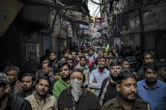People watch from an alleyway as firefighters try to douse a fire that broke out at the congested Bhagirath Palace, a market for electrical goods, in New Delhi, India, Friday, November 25, 2022. No deaths or injuries were reported so far. (Photo by Altaf Qadri/AP Photo)