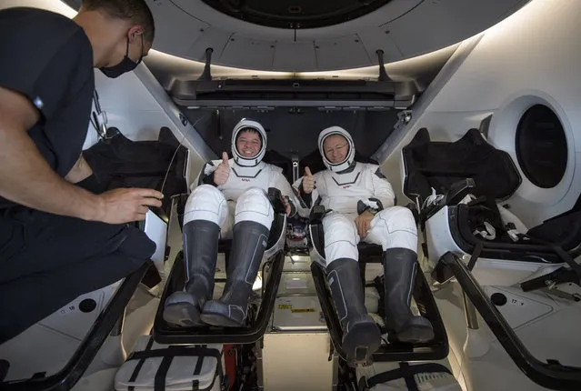 NASA astronauts Robert Behnken, left, and Douglas Hurley are seen inside the SpaceX Crew Dragon Endeavour spacecraft onboard the SpaceX GO Navigator recovery ship shortly after having landed in the Gulf of Mexico off the coast of Pensacola, Fla., Sunday, August 2, 2020. The Demo-2 test flight for NASA's Commercial Crew Program was the first to deliver astronauts to the International Space Station and return them safely to Earth onboard a commercially built and operated spacecraft. Behnken and Hurley returned after spending 64 days in space. (Photo by Bill Ingalls/NASA via AP Photo)
