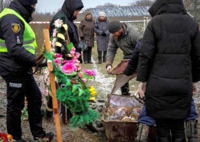 Tamila Pehyda, 67, attends an exhumation of her husband Serhii, 70, who was killed by shrapnel during a Russian missiles attack on June 21 in the village of Vysokopillia, Kherson region, Ukraine on December 5, 2022. (Photo by Anna Voitenko/Reuters)