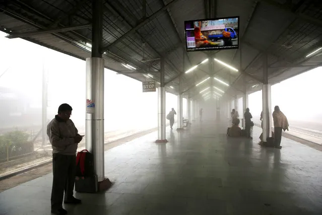 Passengers wait for a train amidst early morning dense fog at a railway station in Lucknow, India, Monday, December 25, 2017. In the winter months, northern India experiences fog enveloped mornings that reduce visibility severely, often leading to delays and cancellation of trains and flights. (Photo by Rajesh Kumar Singh/AP Photo)