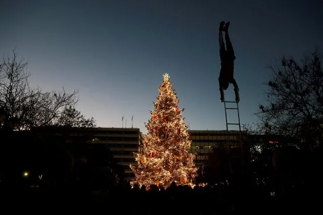 A street artist performs in front of the Christmas tree at Syntagma Square during Christmas festivities in Athens, Greece on December 25, 2022. (Photo by Costas Baltas/Reuters)