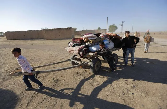 Kurdish Syrian refugees carry their belongings after crossing the Turkish-Syrian border, near the southeastern town of Suruc in Sanliurfa province in this September 26, 2014 file photo. (Photo by Murad Sezer/Reuters)