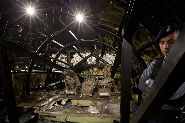 A Dutch Military Policeman guards part of the reconstructed cockpit, rear, and forward section of the fuselage after the Dutch Safety Board presented it's final report into what caused Malaysia Airlines Flight 17 to break up high over Eastern Ukraine last year, killing all 298 people on board, during a press conference in Gilze-Rijen, central Netherlands, Tuesday, October 13, 2015. (Photo by Peter Dejong/AP Photo)