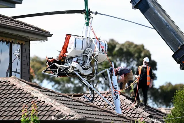 Emergency services remove the wreckage of a helicopter from the roof of a home in Mentone, a suburb of Melbourne, Australia, 30 November 2022. The pilot was taken to the hospital after his aircraft crashed. (Photo by Joel Carrett/EPA/EFE)