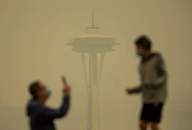 People take photos against the backdrop of the Space Needle as smoke from wildfires fills the air at Kerry Park on September 12, 2020 in Seattle, Washington. According to the National Weather Service, the air quality in Seattle remained at “unhealthy” levels Saturday after a large smoke cloud from wildfires on the West Coast settled over the area. (Photo by Lindsey Wasson/Getty Images)